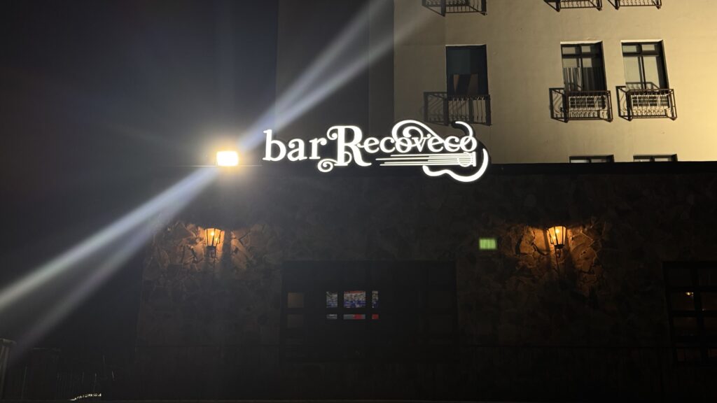 Letrero bar Recoveco en blanco iluminado de noche en fachada