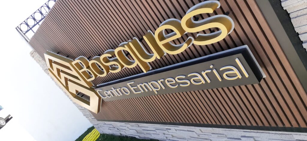 Letrero Bosques dorado script con rombo Centro Empresarial plateado pared corrugada
