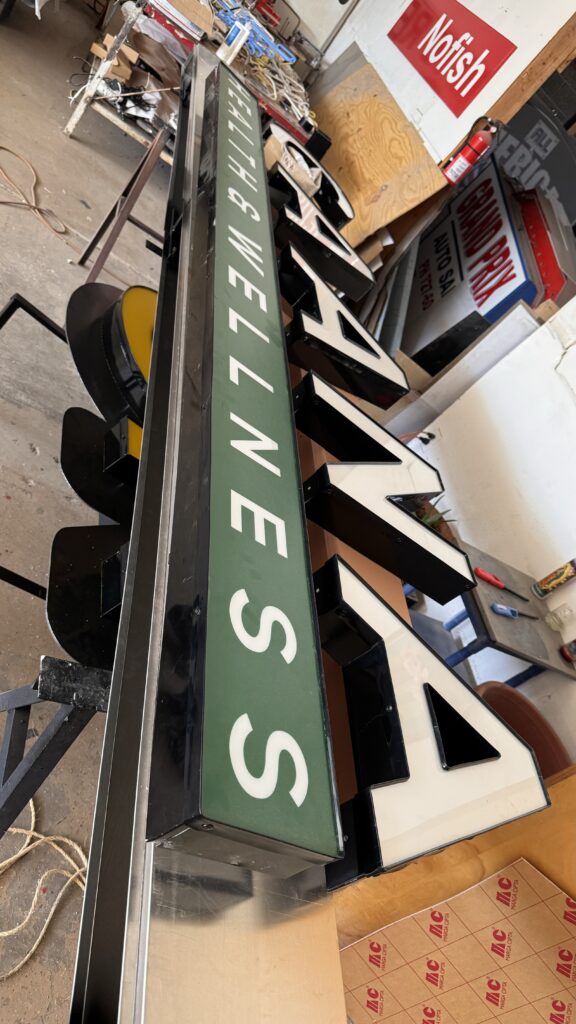 Letras Caana Health Wellness en verde oscuro sueltas en fabricación taller