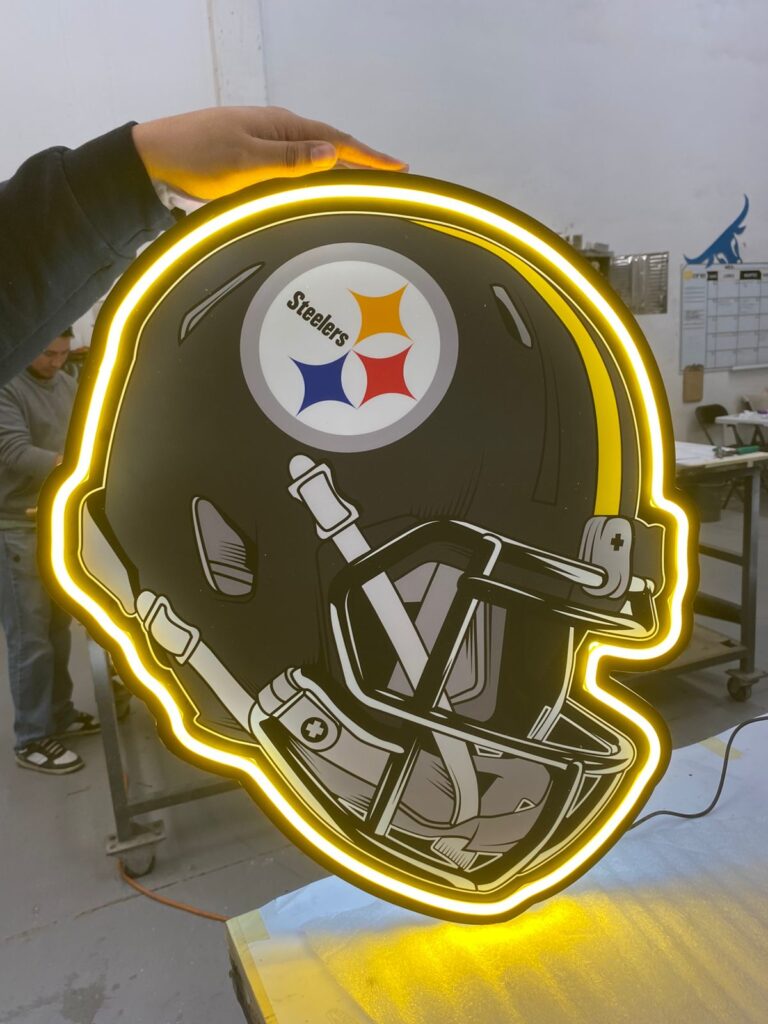 Letrero luminoso casco Steelers con logo equipo en neon amarillo en taller