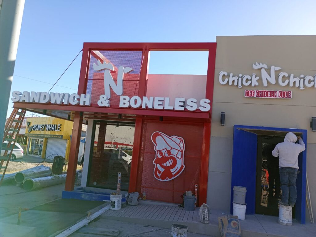 Fachada con letrero Sandwich and Boneless mascota troquelada y puerta azul