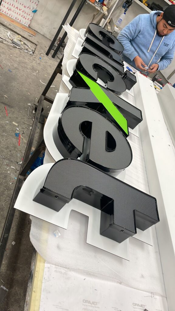 Letras Cricket verde con silueta de grillo negro en fabricación