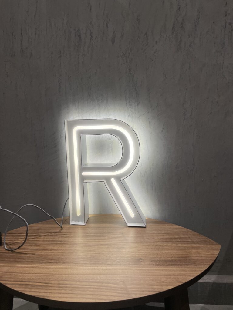 Letra R blanca iluminada para Crown Dollar sobre superficie de madera