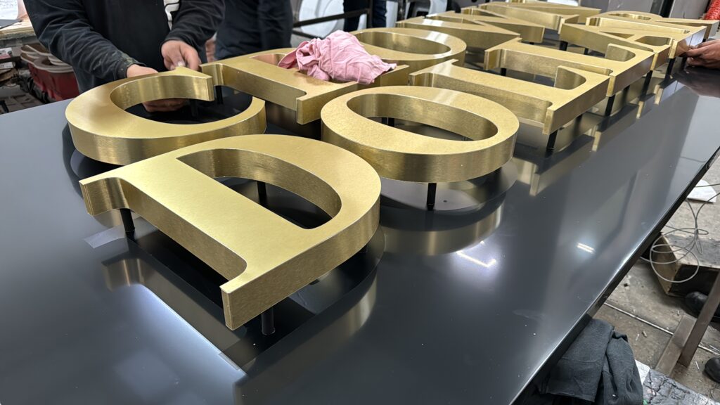 Letras doradas Crown Dollar siendo fabricadas en taller, multiples piezas