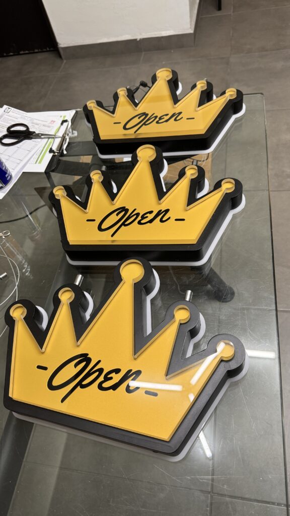 Tres letreros Open en forma de corona amarillos con LED en diferentes tamanos