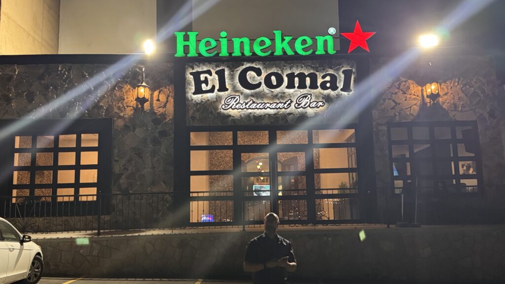 Fachada El Comal de noche con logo Heineken verde, estrella roja e iluminación