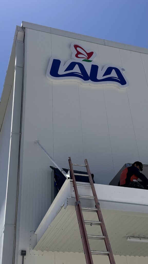 Letrero Lala con logo oficial azul rojo instalado en fachada blanca durante día