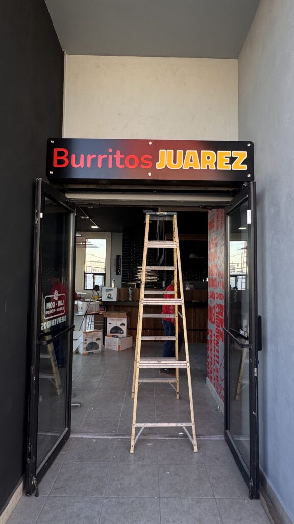 Letrero Drive Thru amarillo fluorescente en pared gris con marco rojo noche