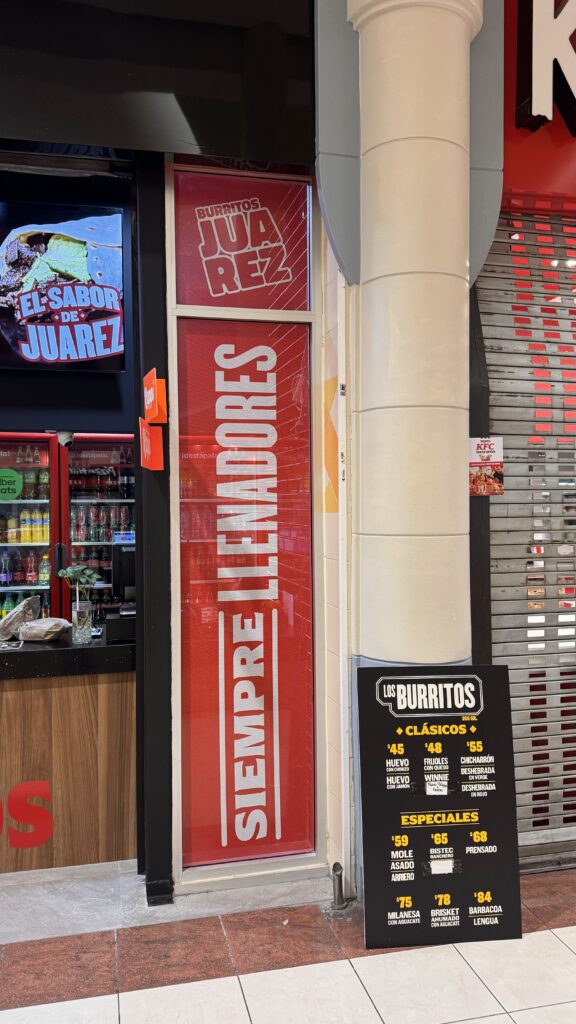 Entrada frontal letrero Burritos Juárez rojo amarillo y tablero de precios