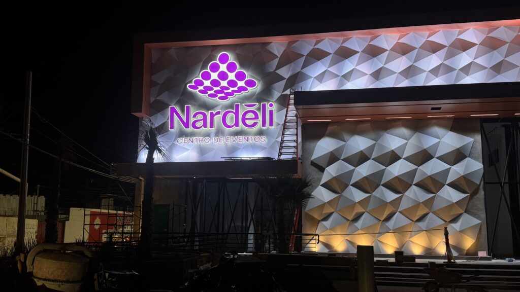 Entrada Nardeli Centro de Eventos con letrero y tótem morado rodeado piedras