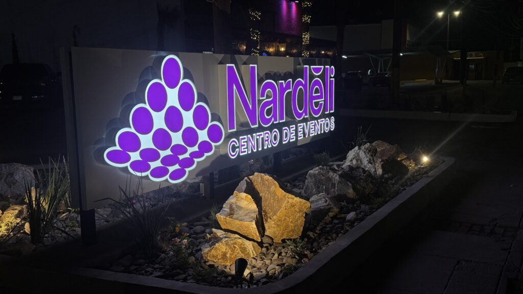 Tótem Nardeli morado con logo uvas rodeado de piedras decorativas iluminadas