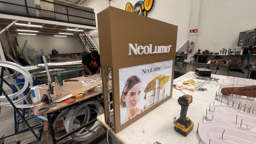 Caja luminosa NeoLumo cafe dorado con panel imagen producto cuidado piel