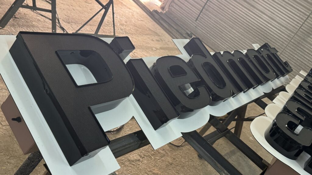 Letras Piedmont Plastics en negro fabricación en taller con estructura soporte
