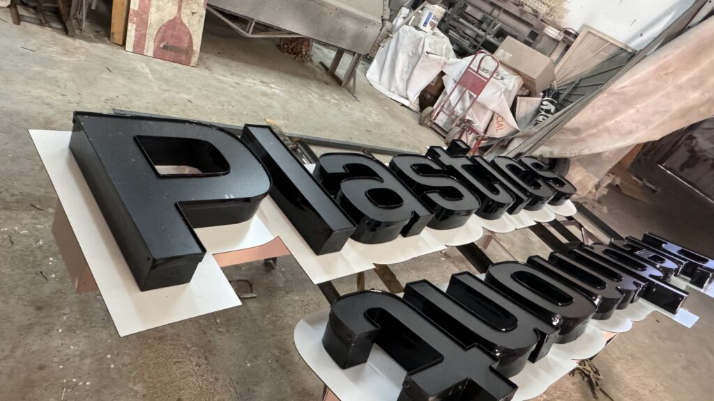 Letras grandes Piedmont Plastics negro en fabricación en taller vista cercana
