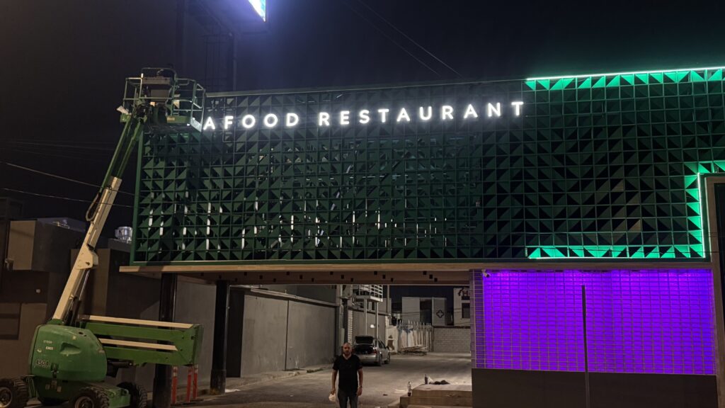 Fachada Toque de Senson de noche con panel verde y letras iluminadas