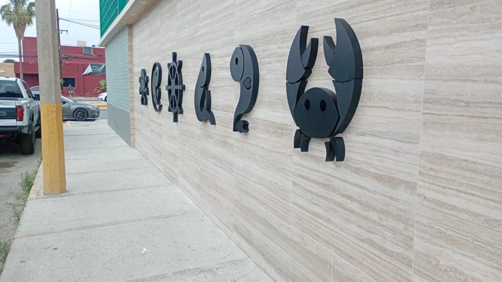 Muro de piedra con iconos marinos negros concha timón pez cangrejo