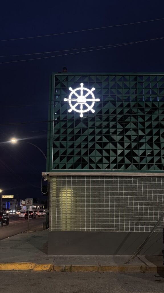 Panel verde noche con timón blanco y letras blancas iluminadas
