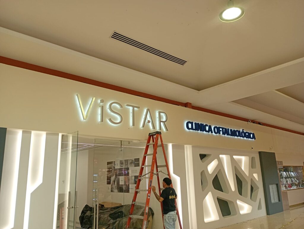 Proceso de instalación de letrero neon Vistar en fachada con escalera roja