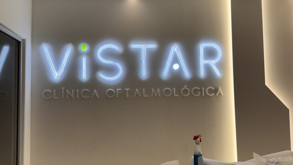 Neon Vistar turquesa con Clínica Oftalmológica en gris sobre pared beige interior