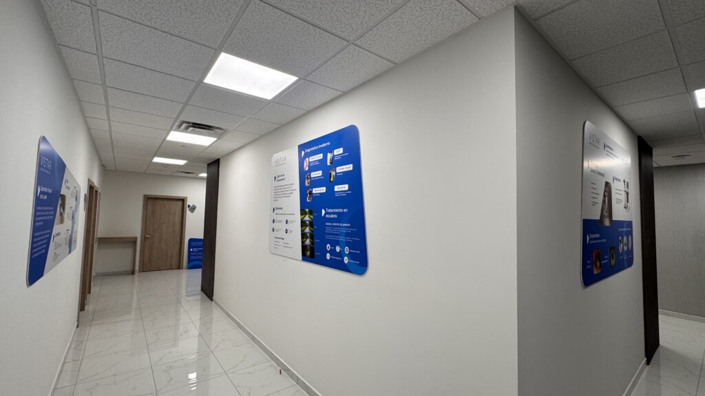 Pasillo interior con tres impresiones digitales azules mostrando servicios e información Vistar