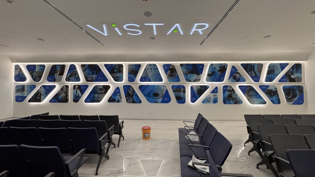 Neon Vistar en techo con logo circular de colores representando ojo en pared interior