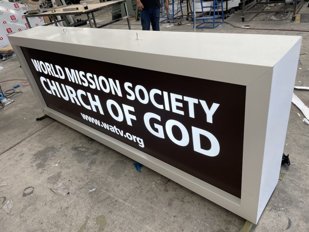 Letrero verde instalado en entrada iglesia con nombre y sitio web blanco